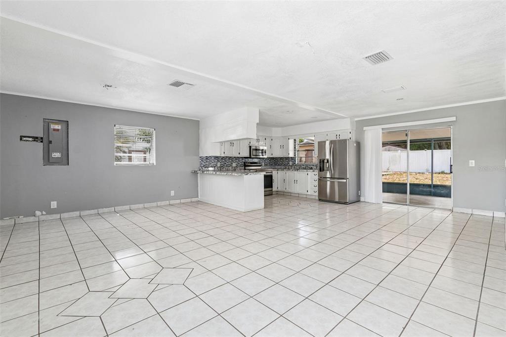 An open-concept kitchen and living area features white tile flooring, gray walls, and stainless appliances — 1719 JULIAN LANE DRIVE, TAMPA, FL