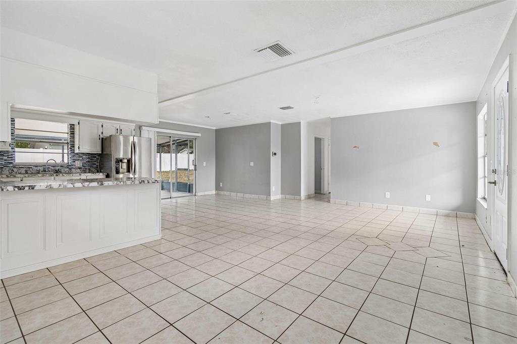 An open-concept living and dining area features white tile flooring, gray walls, and a kitchen — 1719 JULIAN LANE DRIVE, TAMPA, FL