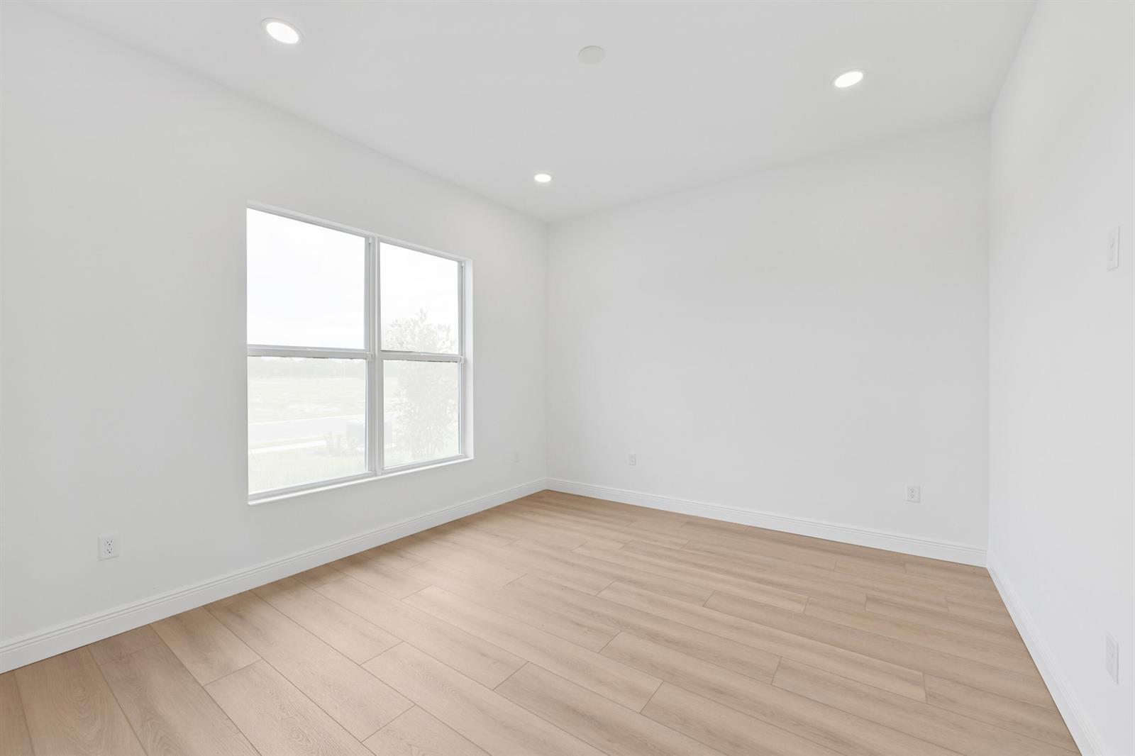 An empty room with white walls, light wood-look flooring, and a large window — 2850 68th Street, Vero Beach FL 32967, VERO BEACH, FL