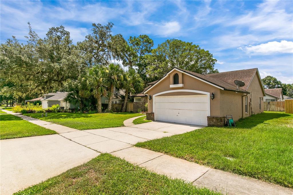 A tan single-story house with a white two-car garage and a concrete driveway — 1322 AMERICAN ELM DRIVE, ALTAMONTE SPRINGS, FL