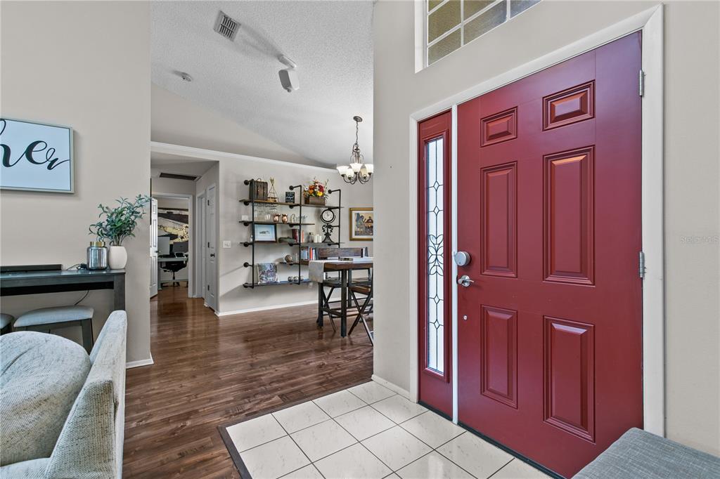 An entryway features a red front door, tiled flooring, and a view into a dining area — 1322 AMERICAN ELM DRIVE, ALTAMONTE SPRINGS, FL