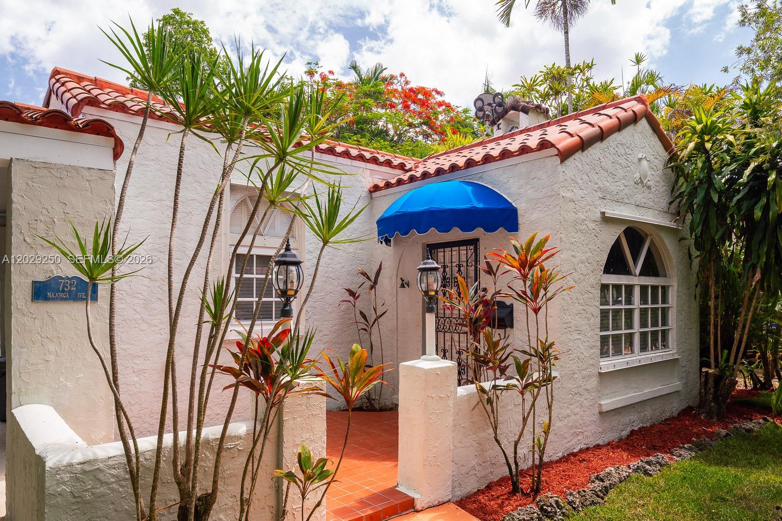 A white stucco house with a red tile roof and a blue arched door awning — 732 Majorca Ave, Coral Gables FL 33134, CORAL GABLES, FL