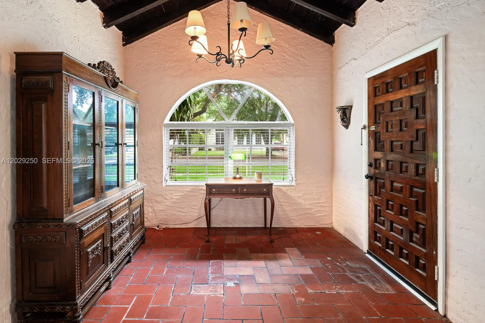 An entryway features a vaulted ceiling, terracotta tile flooring, a wooden hutch, and a front door — 732 Majorca Ave, Coral Gables FL 33134, CORAL GABLES, FL
