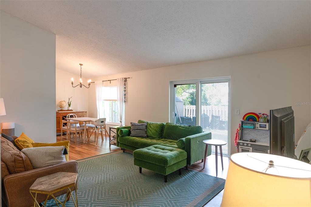 A living room with a green velvet sofa, a brown armchair, and an adjacent dining area — 6805 S GABRIELLE STREET, TAMPA, FL