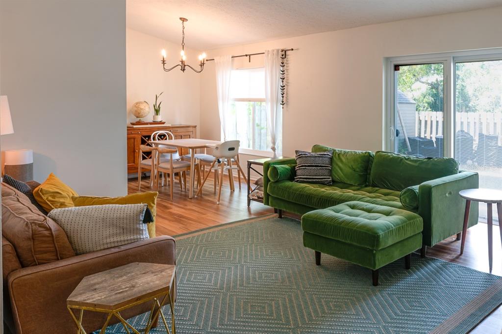 A living room and dining area featuring a green velvet sofa, brown couch, and chandelier — 6805 S GABRIELLE STREET, TAMPA, FL