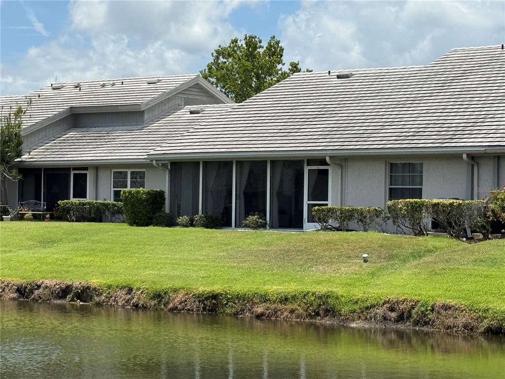 A view of the rear exterior of a single-story house with a screened-in patio — 5371 CRESTLAKE BOULEVARD UNIT 68, SARASOTA, FL