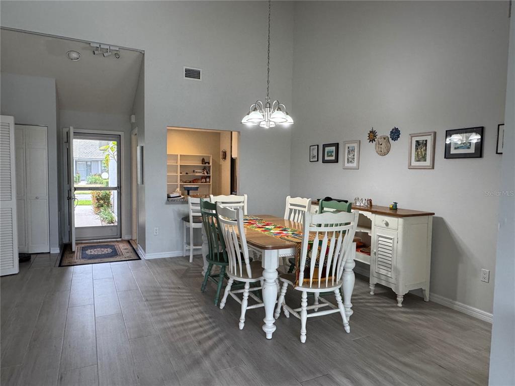 A dining room features a wooden table, white chairs, a sideboard, and light-colored flooring — 5371 CRESTLAKE BOULEVARD UNIT 68, SARASOTA, FL