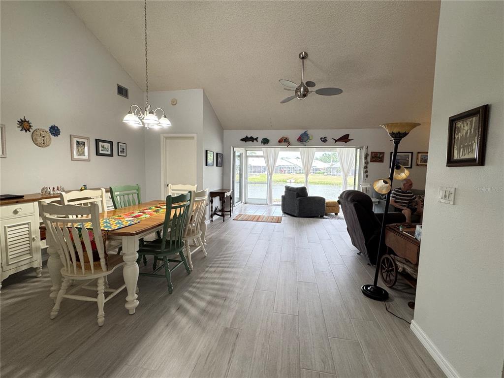 An open-concept dining and living area features vaulted ceilings, tile flooring, and a water view — 5371 CRESTLAKE BOULEVARD UNIT 68, SARASOTA, FL