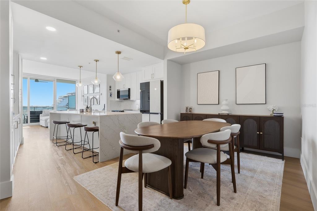 A modern dining area features a wooden table, upholstered chairs, and a kitchen island nearby — 912 CHANNELSIDE DRIVE UNIT 2503, TAMPA, FL