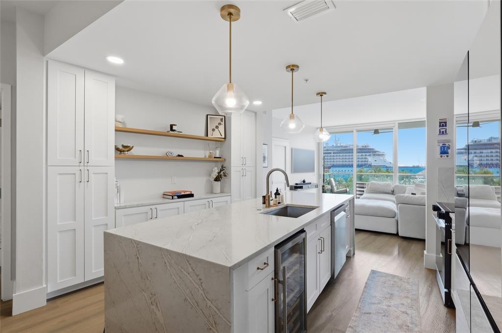 A modern kitchen features a marble-topped island, white cabinetry, and a view of cruise ships — 912 CHANNELSIDE DRIVE UNIT 2503, TAMPA, FL