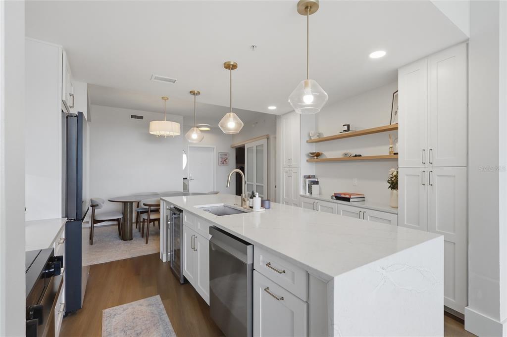 A modern kitchen features a white quartz island, stainless steel appliances, and open wooden shelving — 912 CHANNELSIDE DRIVE UNIT 2503, TAMPA, FL