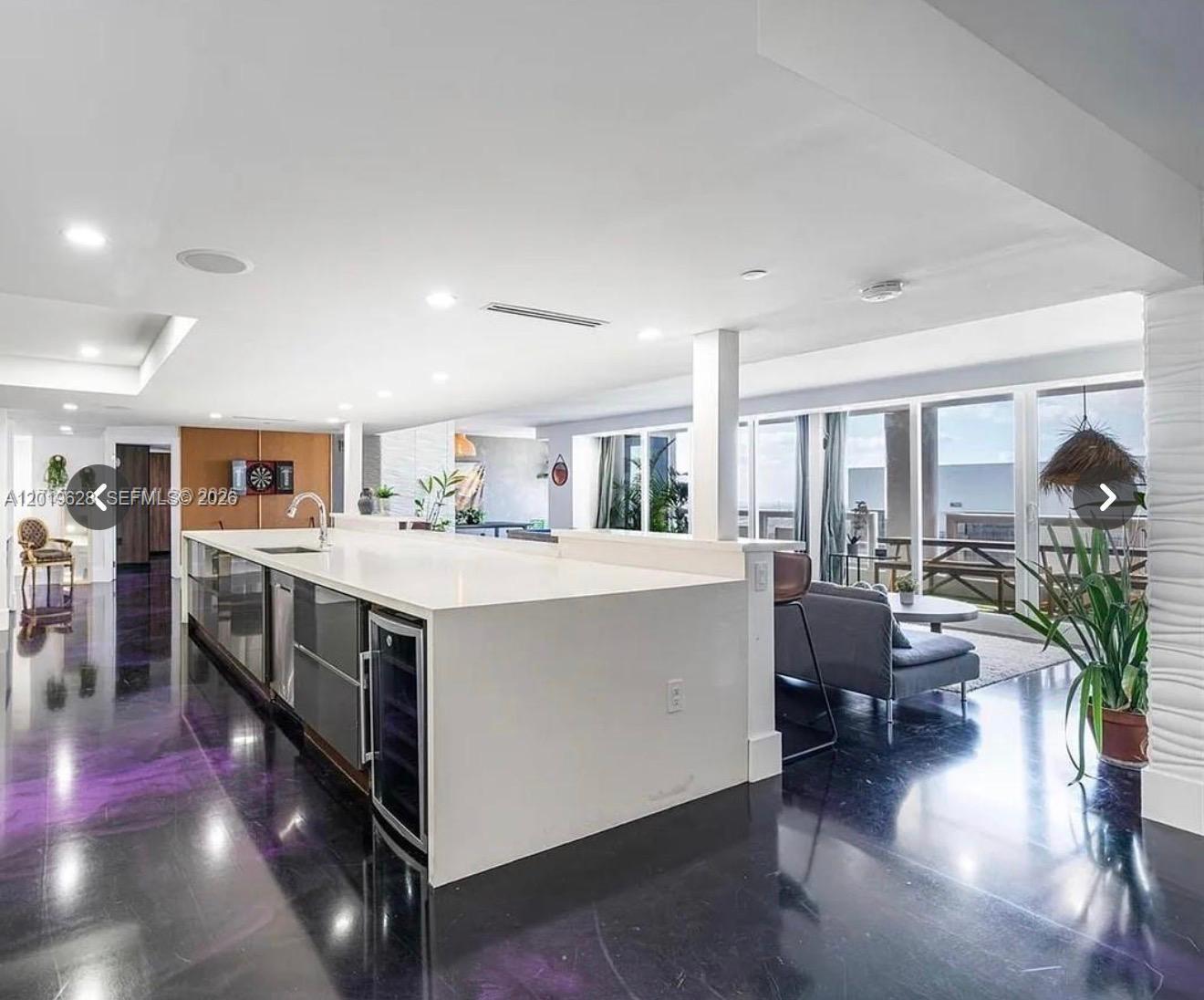 A modern kitchen with a large white island overlooks a living area and balcony — 1717 N Bayshore Dr # 3545, Miami FL 33132, MIAMI, FL