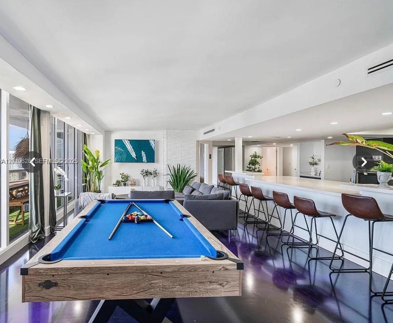 A living area features a blue pool table, a grey sofa, and a long breakfast bar — 1717 N Bayshore Dr # 3545, Miami FL 33132, MIAMI, FL