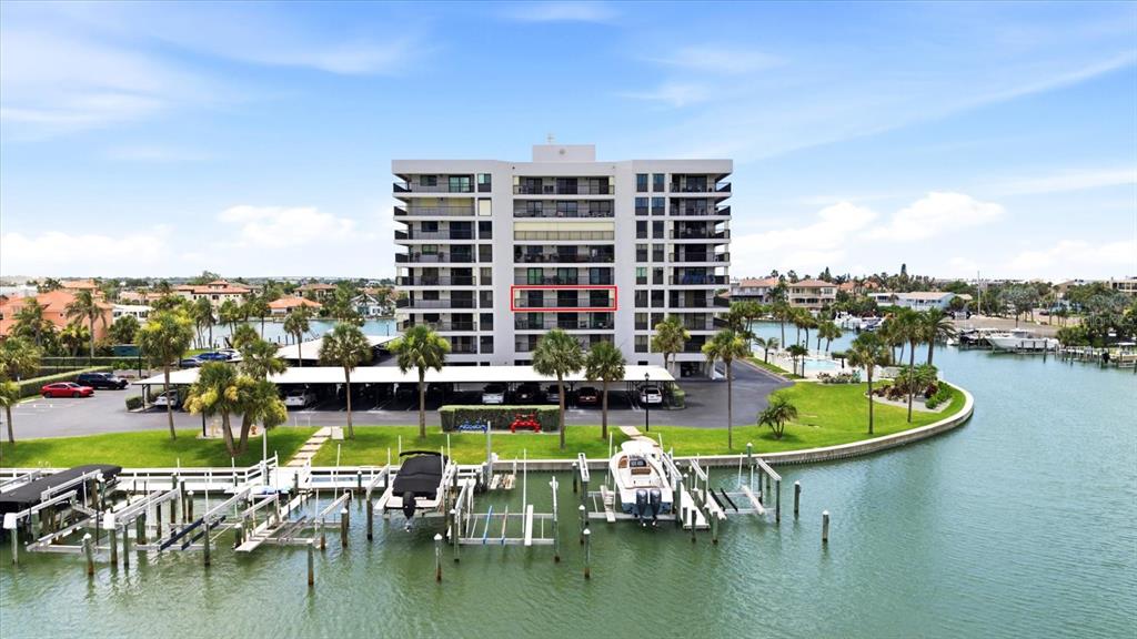 An aerial view shows a multi-story waterfront condominium building with a boat dock — 1651 SAND KEY ESTATES COURT UNIT 31, CLEARWATER, FL
