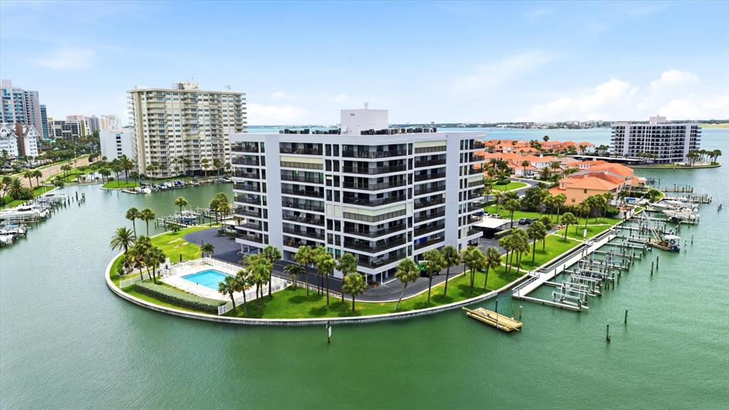 An aerial view of a multi-story apartment building on a waterfront peninsula with a pool — 1651 SAND KEY ESTATES COURT UNIT 31, CLEARWATER, FL