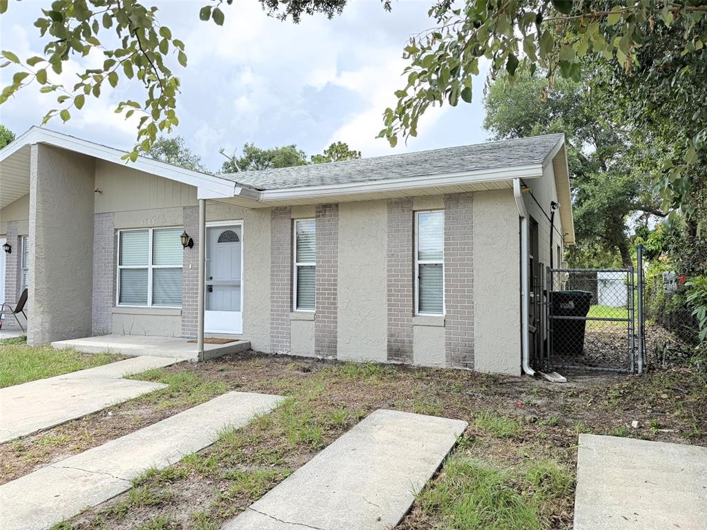 A single-story duplex with a light-colored stucco and brick facade and a concrete driveway — 8103 PUFFIN DRIVE, ORLANDO, FL