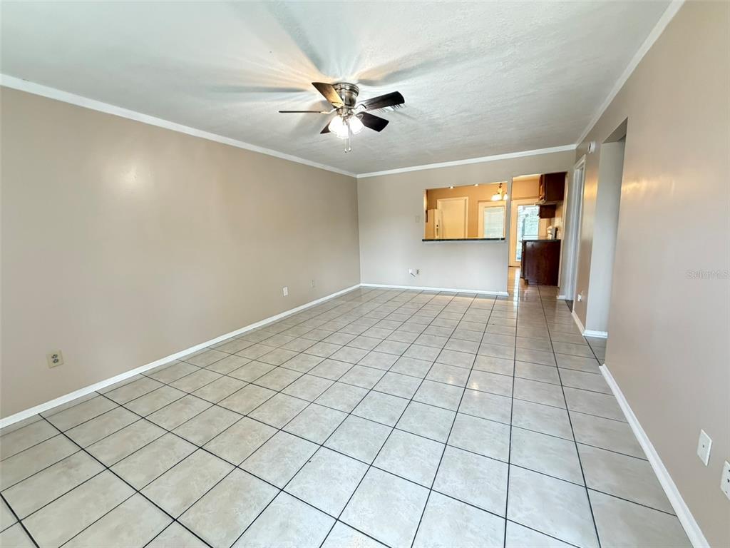 An empty room with beige walls, a ceiling fan, and light-colored square floor tiles — 8103 PUFFIN DRIVE, ORLANDO, FL