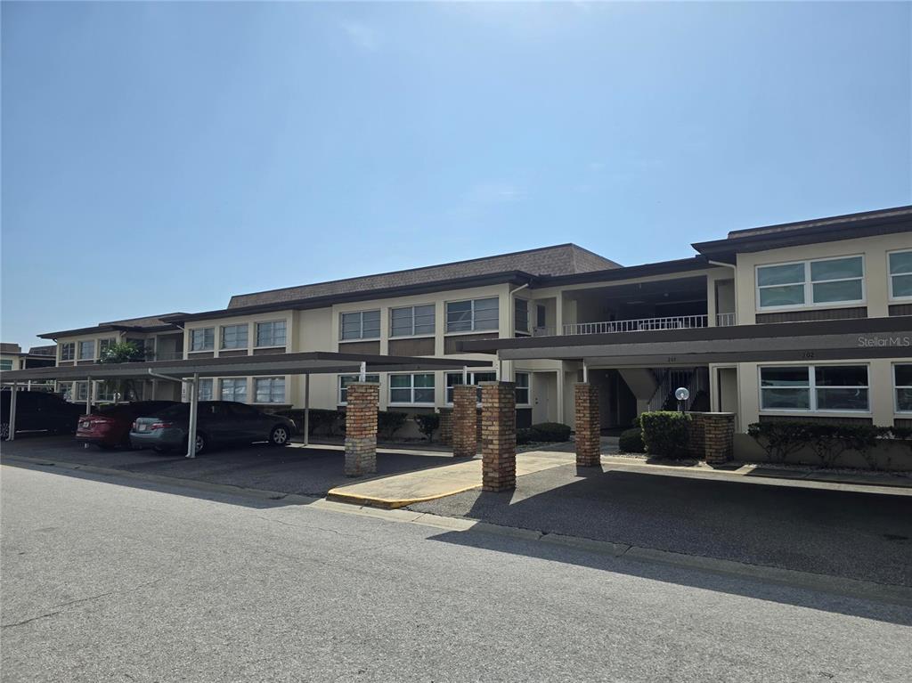 A multi-story apartment building with covered parking spaces and brick support pillars — 5111 AMULET DRIVE UNIT 104, NEW PORT RICHEY, FL