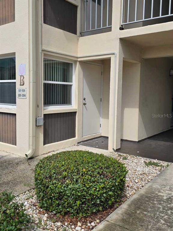An exterior view of a building entrance with a beige door and a round bush — 5111 AMULET DRIVE UNIT 104, NEW PORT RICHEY, FL