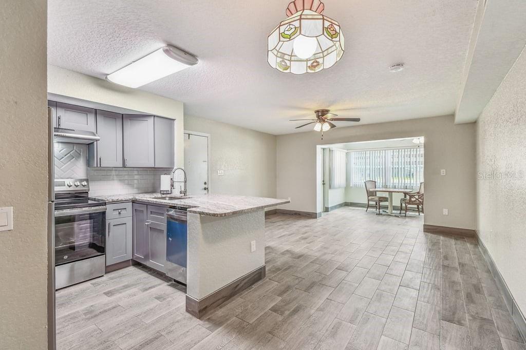 A kitchen with grey cabinets and a granite island opens into a dining area — 5111 AMULET DRIVE UNIT 104, NEW PORT RICHEY, FL