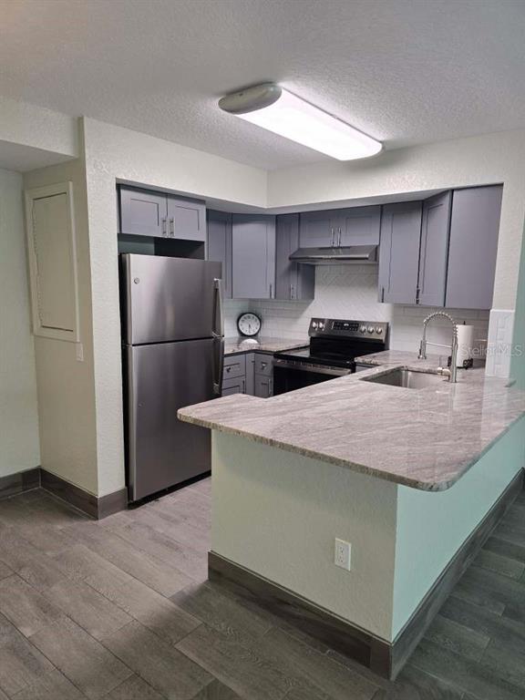 A kitchen features gray cabinets, stainless steel appliances, and a granite-topped peninsula — 5111 AMULET DRIVE UNIT 104, NEW PORT RICHEY, FL