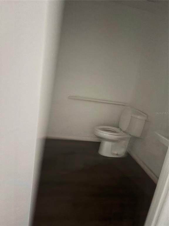 A small bathroom features a white toilet and dark flooring against plain white walls — 19800 VETERANS BOULEVARD UNIT E4, PORT CHARLOTTE, FL