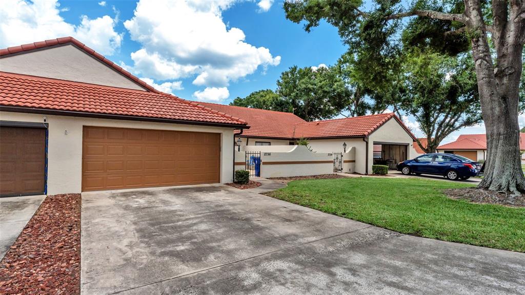 A single-story house with a brown garage door, red tile roof, and a concrete driveway — 2756 DEL CASA COURT UNIT 18, AVON PARK, FL