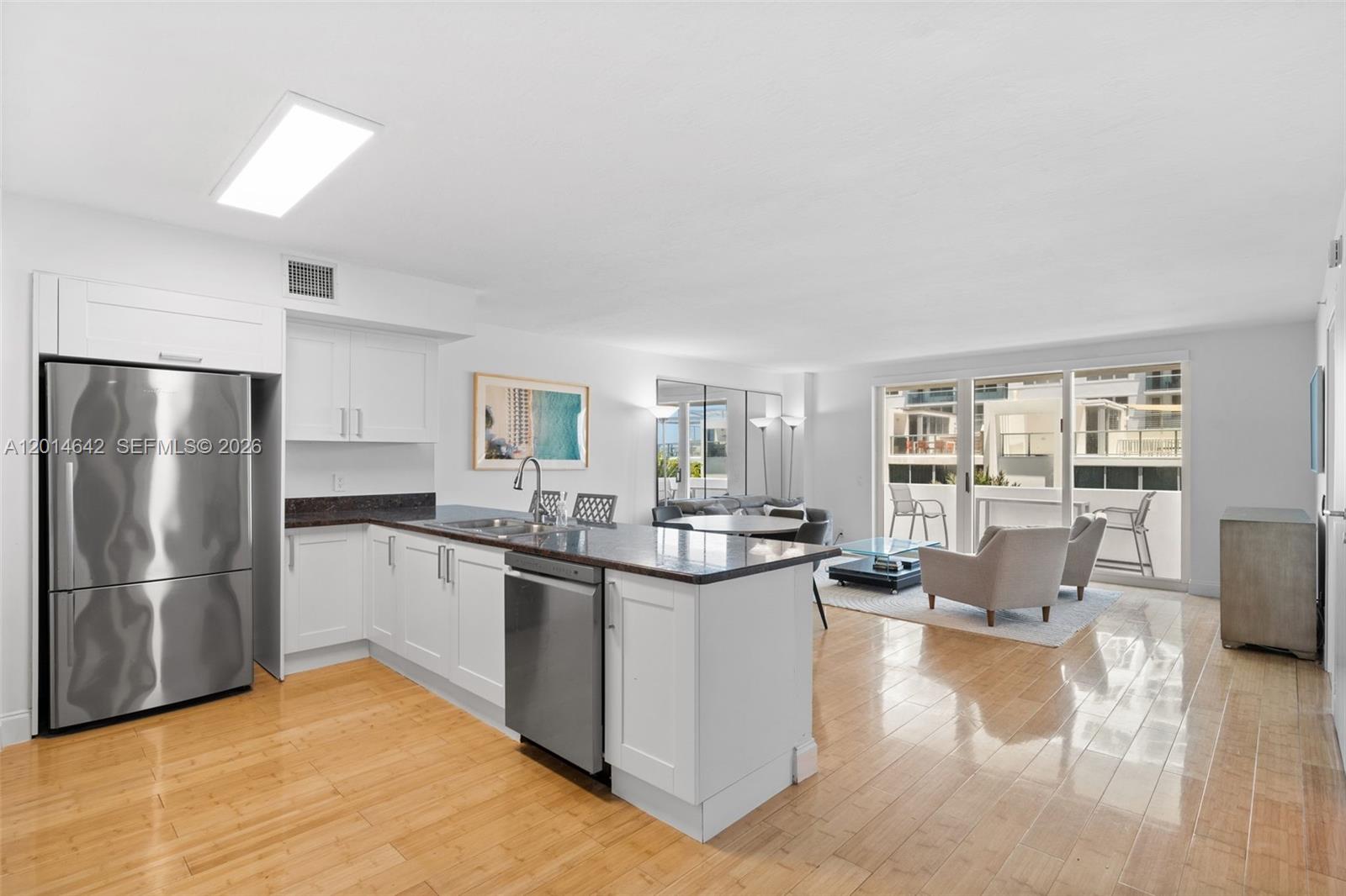 A modern kitchen with stainless steel appliances and white cabinetry opens into a living area — 9499 Collins Ave # 403, Surfside FL 33154, SURFSIDE, FL