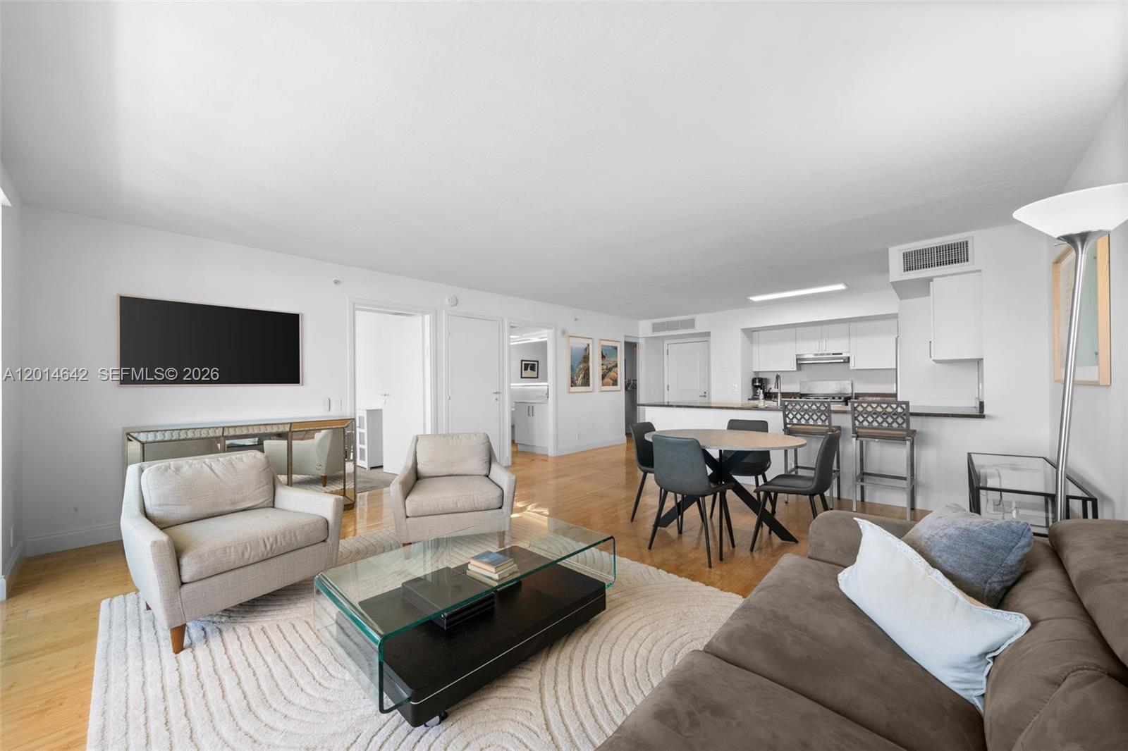 A living room and dining area with light wood floors, white walls, and modern furniture — 9499 Collins Ave # 403, Surfside FL 33154, SURFSIDE, FL