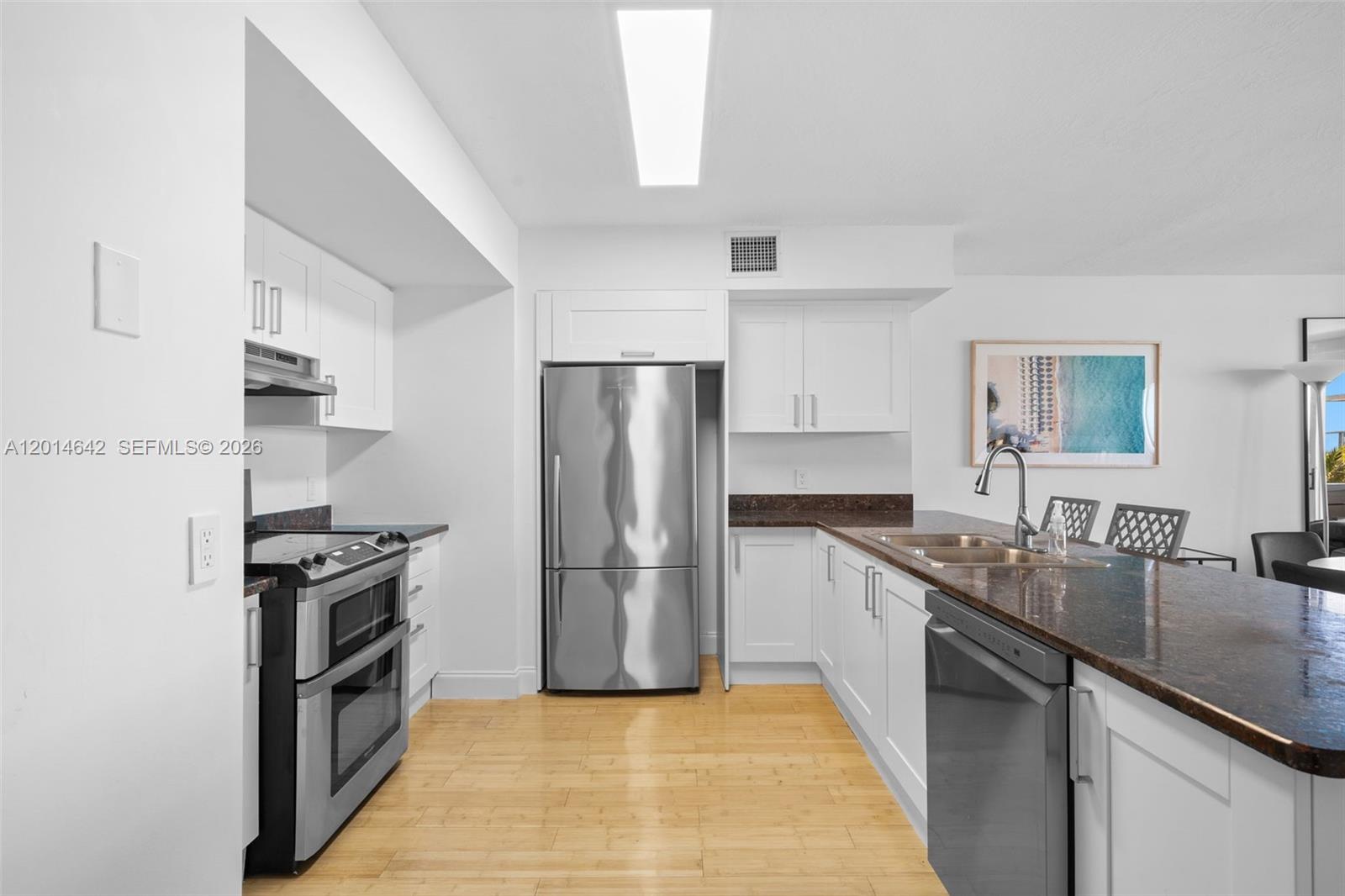 A kitchen features white cabinets, stainless steel appliances, and a dark granite countertop island — 9499 Collins Ave # 403, Surfside FL 33154, SURFSIDE, FL