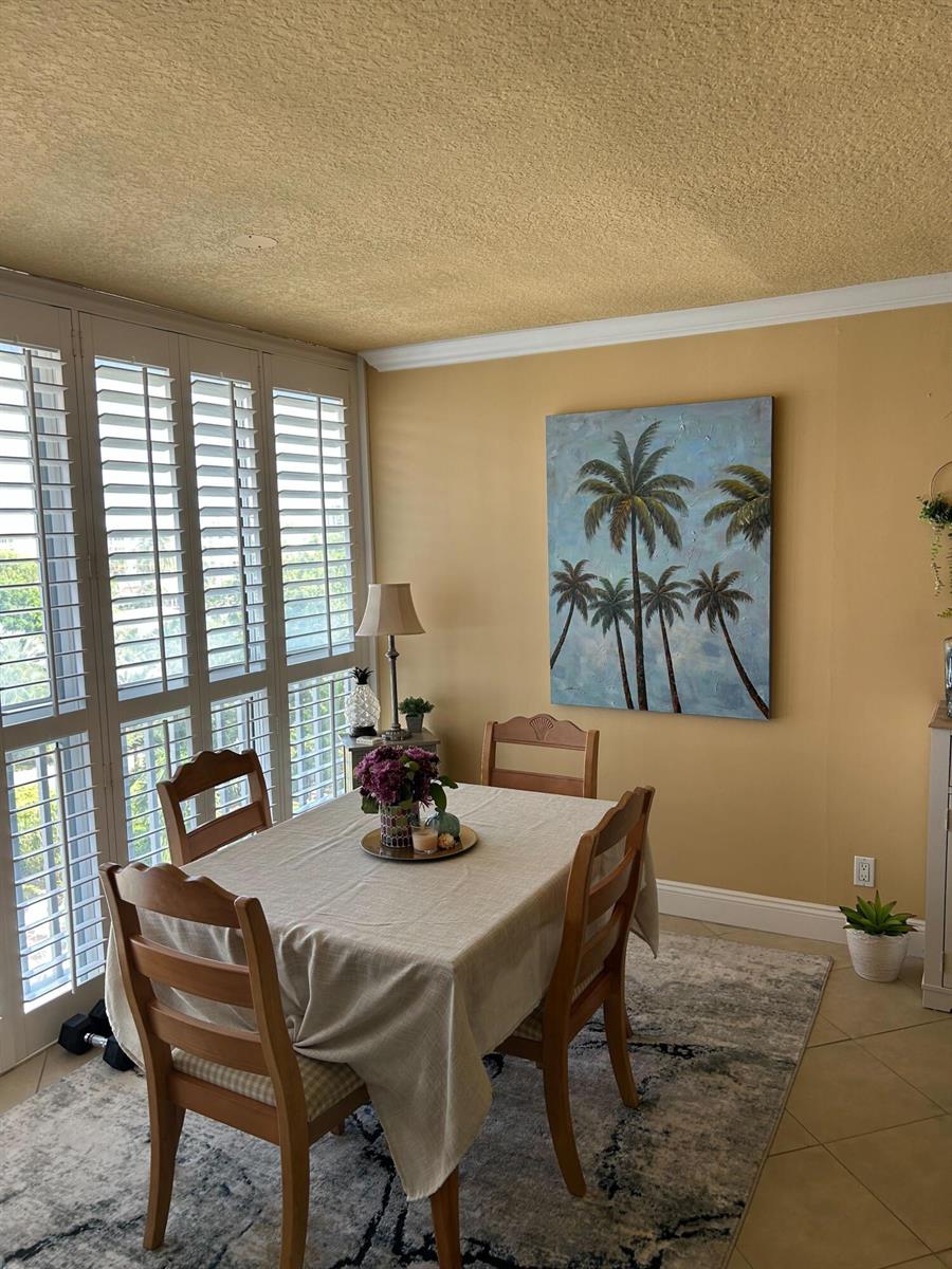 A dining room with a table, chairs, a palm tree painting, and plantation shutters — 2829 Florida Boulevard # 502, Delray Beach FL 33483, DELRAY BEACH, FL