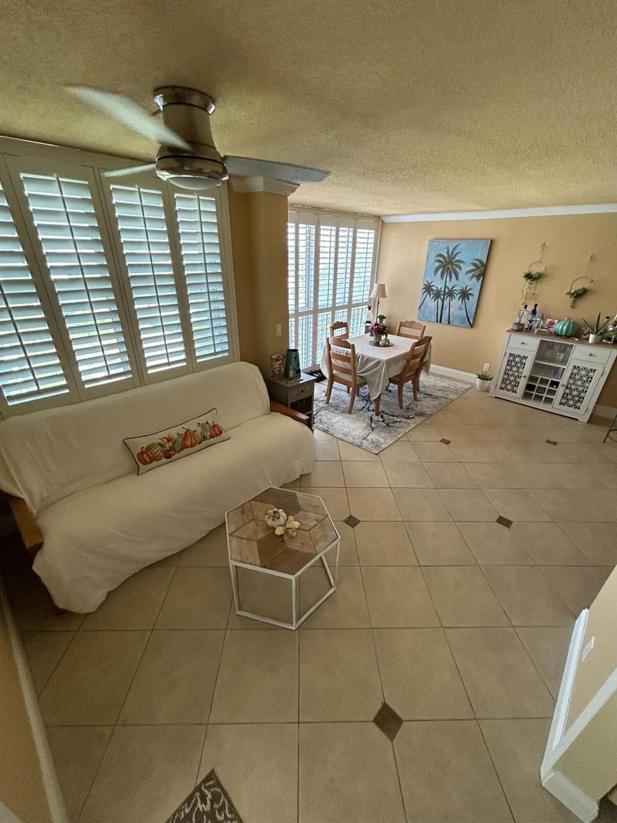 A living and dining area features tile floors, plantation shutters, and a white sofa — 2829 Florida Boulevard # 502, Delray Beach FL 33483, DELRAY BEACH, FL