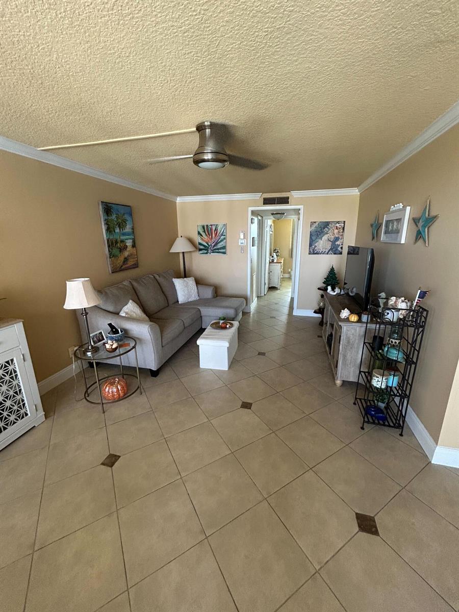 A living room features a sectional sofa, a television console, and tile flooring — 2829 Florida Boulevard # 502, Delray Beach FL 33483, DELRAY BEACH, FL