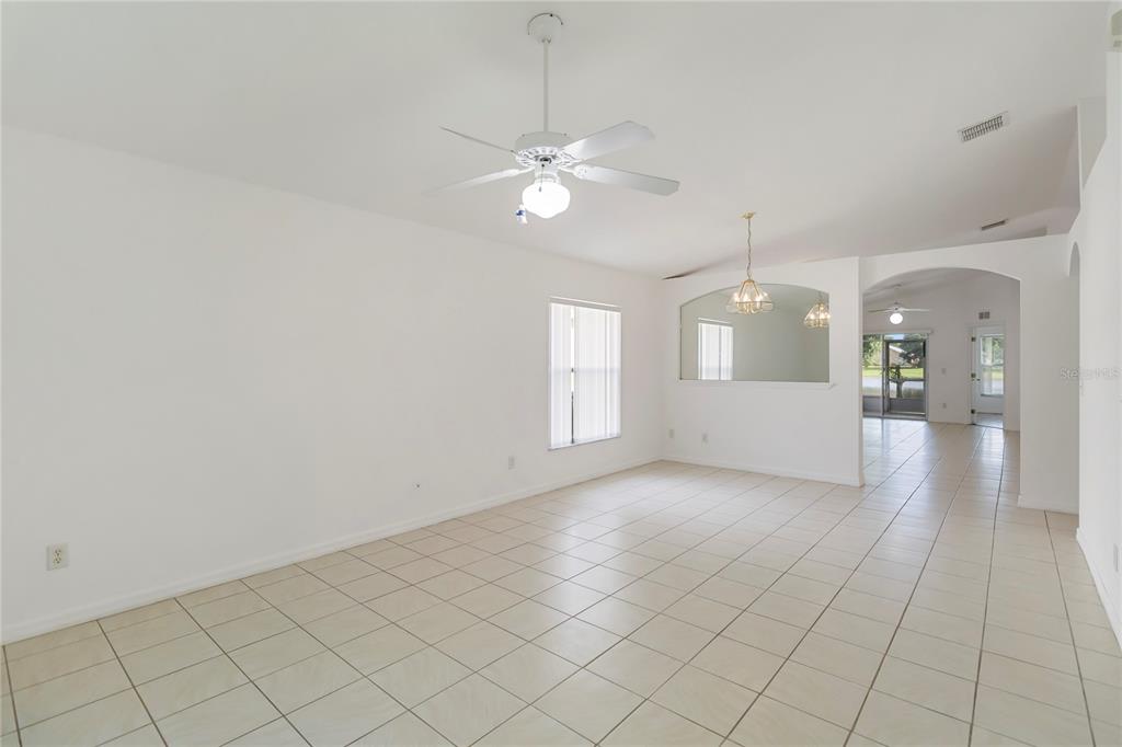 An empty room with white walls, tile flooring, a ceiling fan, and a mirrored wall — 11055 ROUSE RUN CIRCLE, ORLANDO, FL