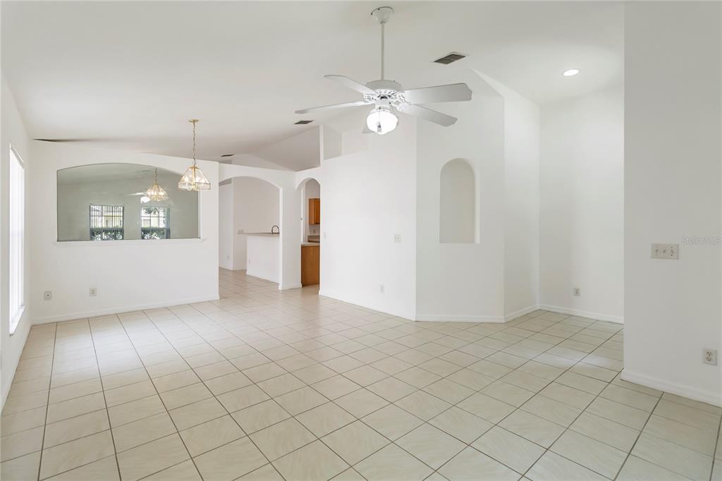 A bright, open-concept living and dining area features white walls, tile flooring, and a ceiling fan — 11055 ROUSE RUN CIRCLE, ORLANDO, FL