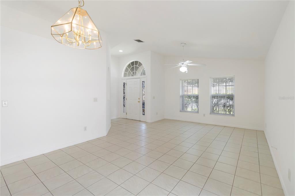 An empty room with white walls, tiled floors, a chandelier, and a front entryway door — 11055 ROUSE RUN CIRCLE, ORLANDO, FL