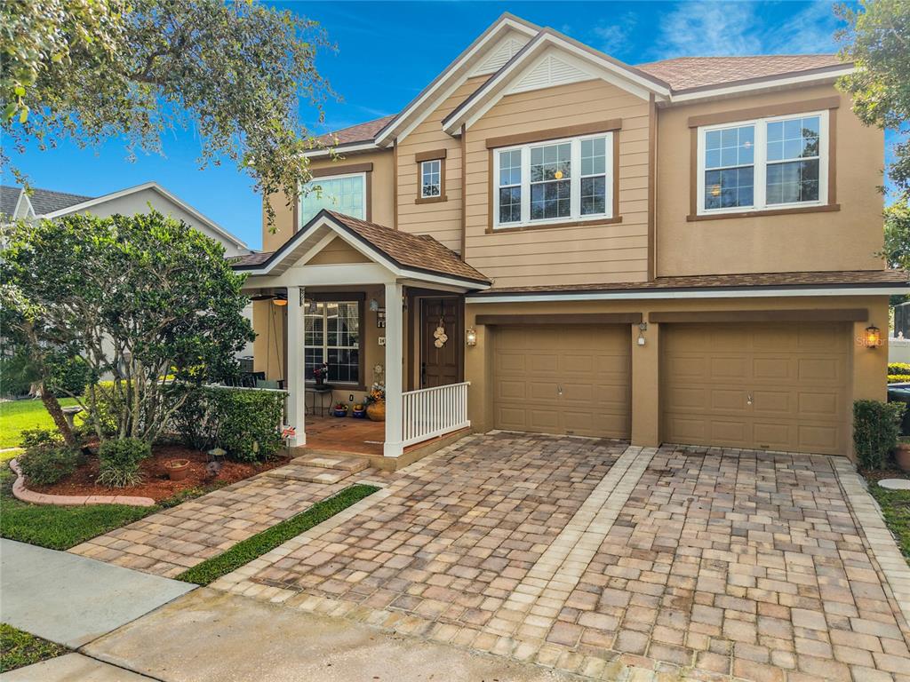 A two-story house with a tan exterior, a paved driveway, and a covered front porch — 14143 LAKE LIVE OAK DRIVE, ORLANDO, FL