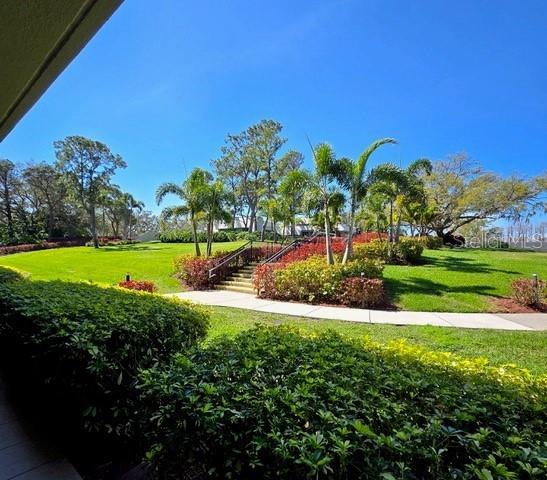 A paved walkway leads up a small set of stairs through a landscaped grassy area — 36750 US HIGHWAY 19 N UNIT 4-107, PALM HARBOR, FL