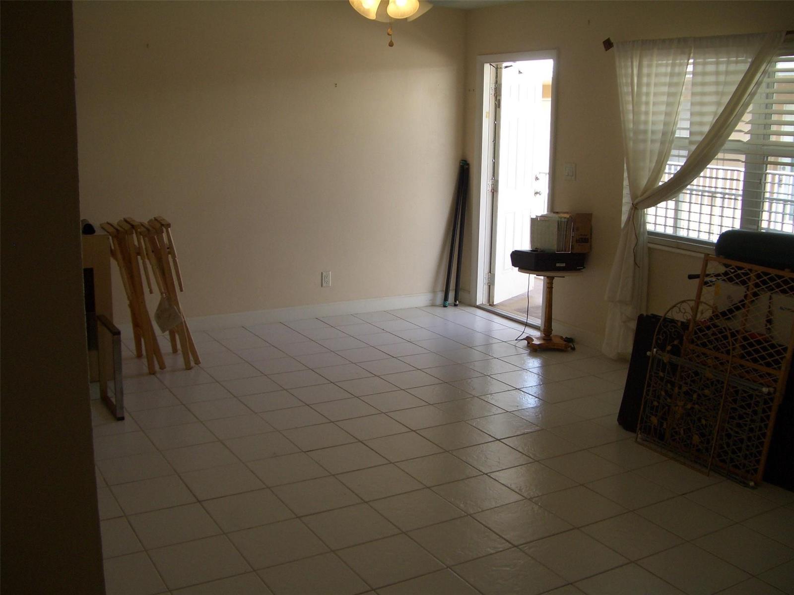 An empty room with white tile flooring, a ceiling fan, and an open exterior door — 2737 NE 28th Street # 7w, Lighthouse Point FL 33064, LIGHTHOUSE POINT, FL