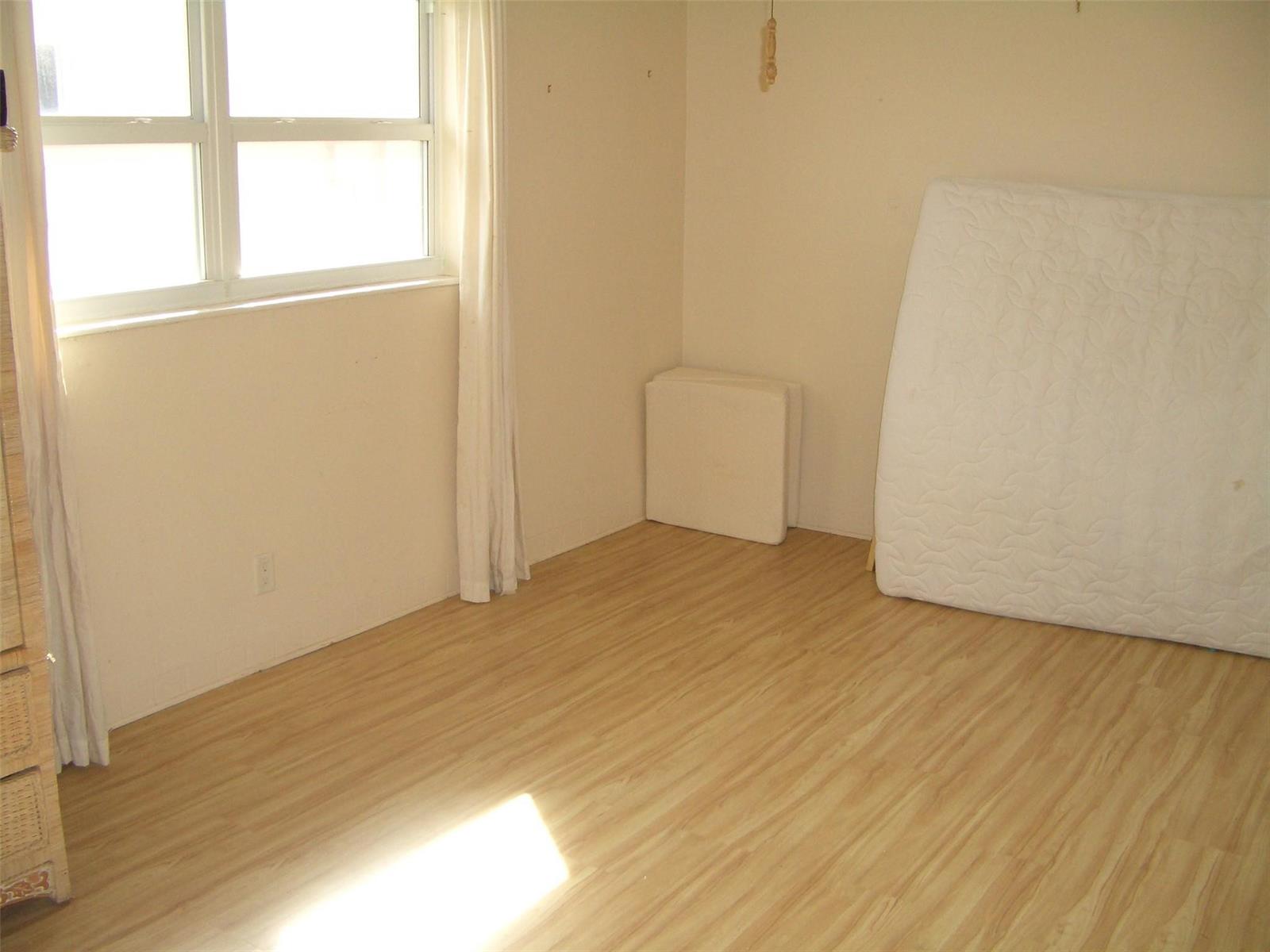 An empty bedroom features light wood-look flooring, beige walls, a window, and a mattress — 2737 NE 28th Street # 7w, Lighthouse Point FL 33064, LIGHTHOUSE POINT, FL