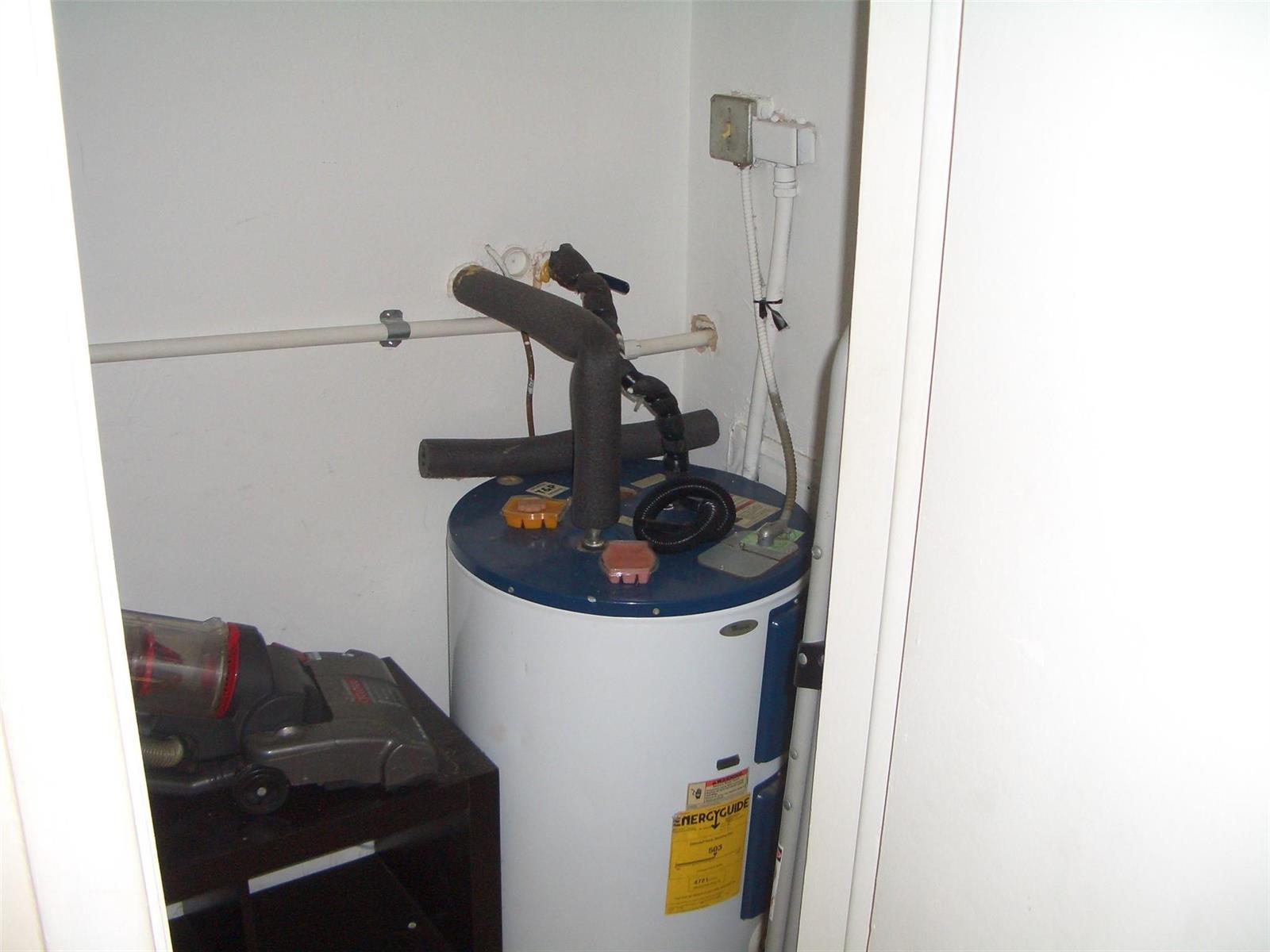 A water heater is located inside a small utility closet next to a vacuum cleaner — 2737 NE 28th Street # 7w, Lighthouse Point FL 33064, LIGHTHOUSE POINT, FL