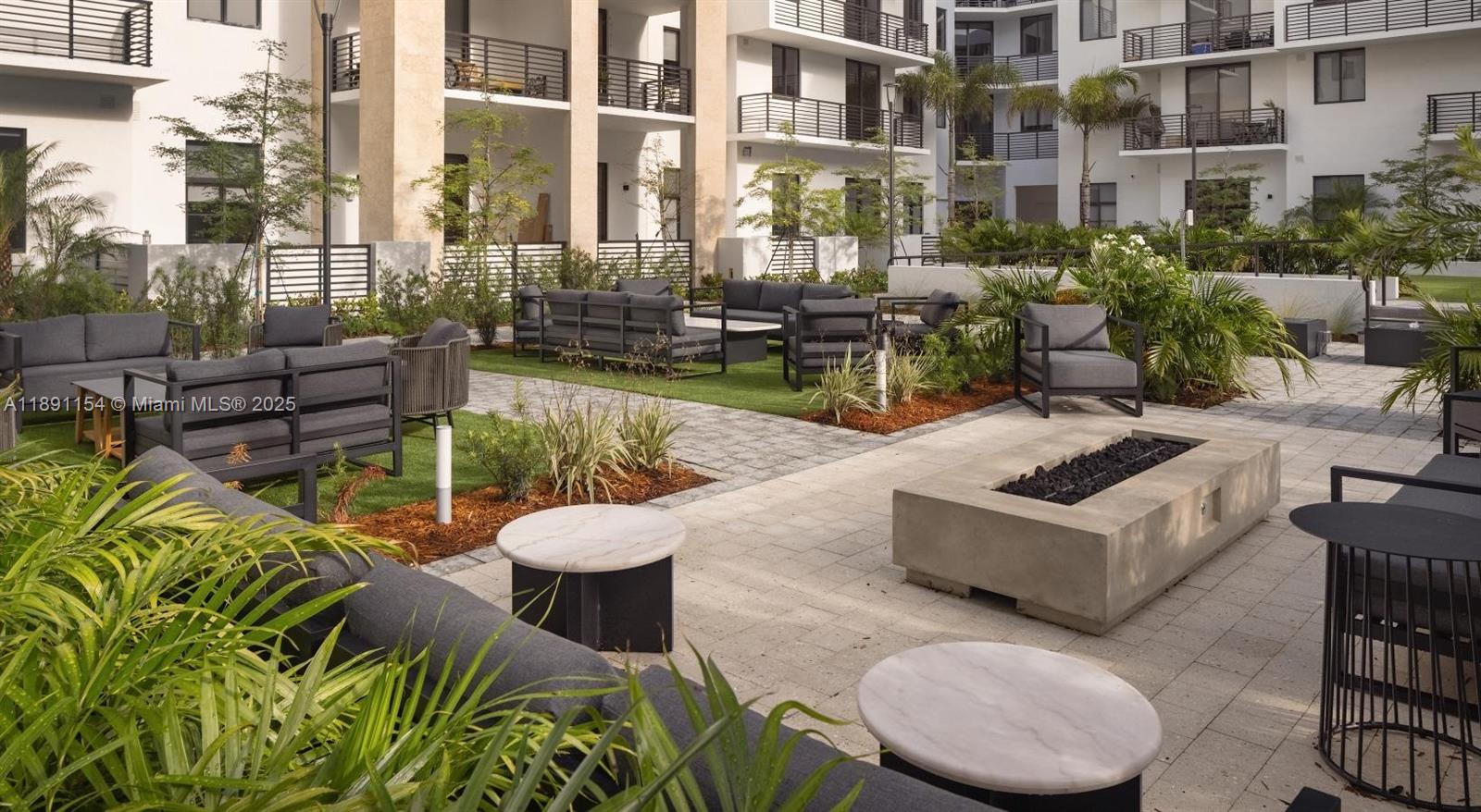 An outdoor courtyard features patio furniture, a concrete fire pit, and landscaping between apartment buildings — 11200 Biscayne Blvd # A1, Miami FL 33181, MIAMI, FL