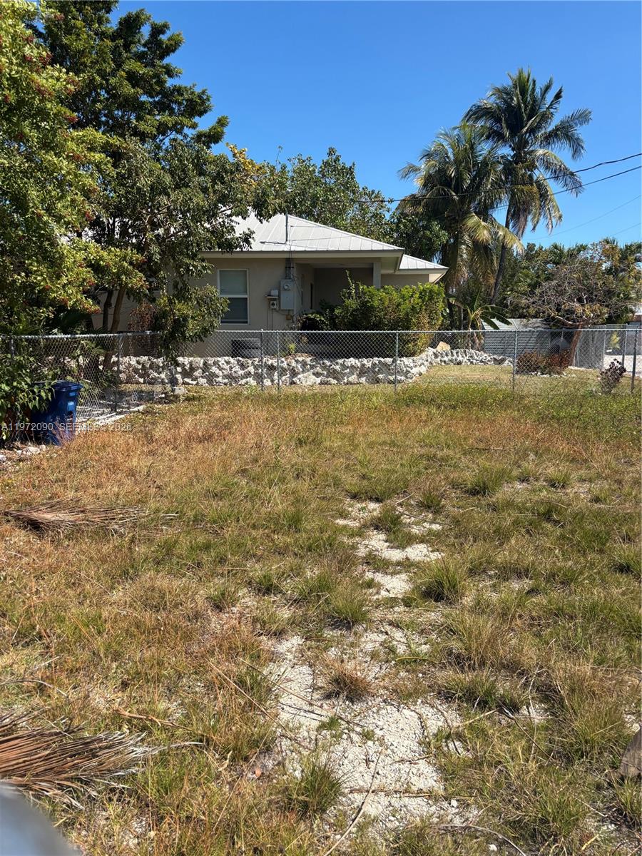 A grassy, undeveloped lot sits in front of a house with a chain-link fence — 319 Tuskegee Street, Marathon FL 33050, MARATHON, FL