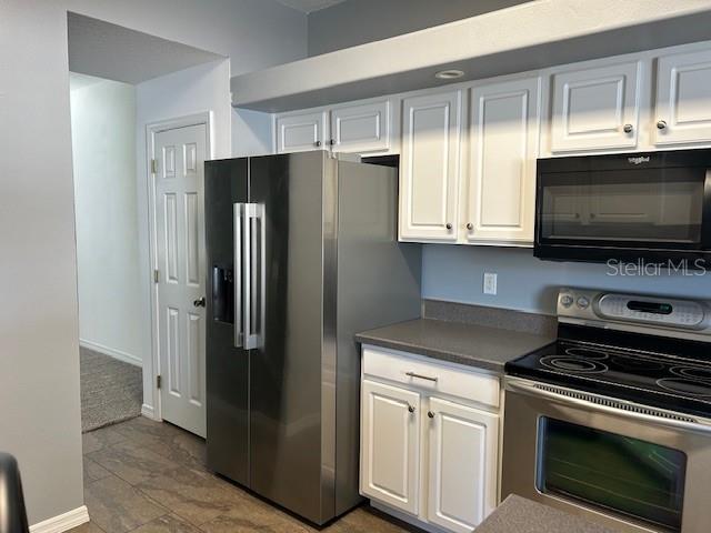 A kitchen features white cabinets, stainless steel appliances, and dark countertops — 12405 CRUXBURY DRIVE, WINDERMERE, FL