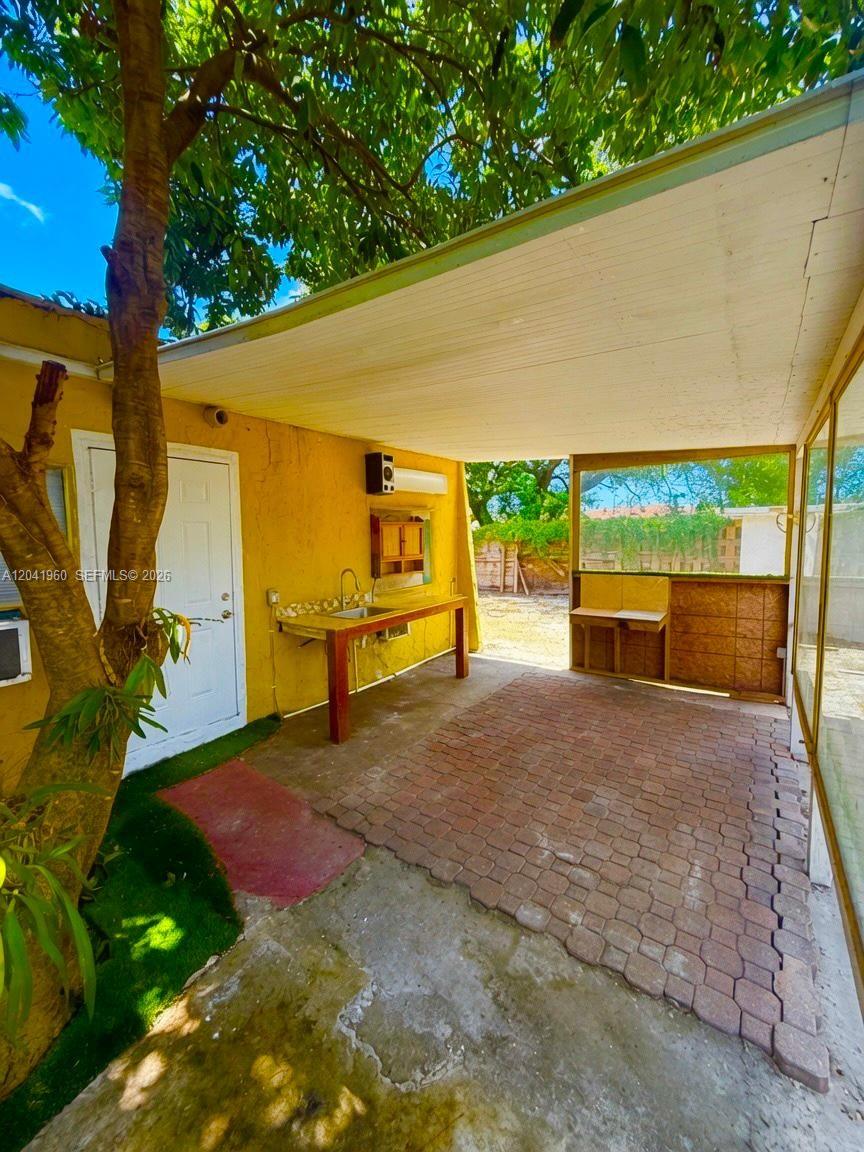 An outdoor covered patio features a brick floor, a sink station, and a white door — 1340 Peri St # U, Opa-Locka FL 33054, OPA-LOCKA, FL