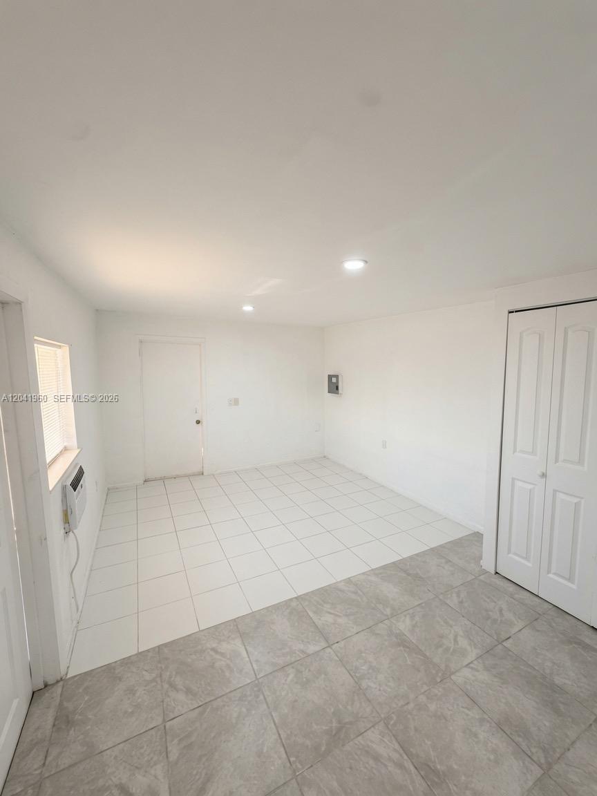 An empty room features white walls, tile flooring, a window, and a white closet door — 1340 Peri St # U, Opa-Locka FL 33054, OPA-LOCKA, FL