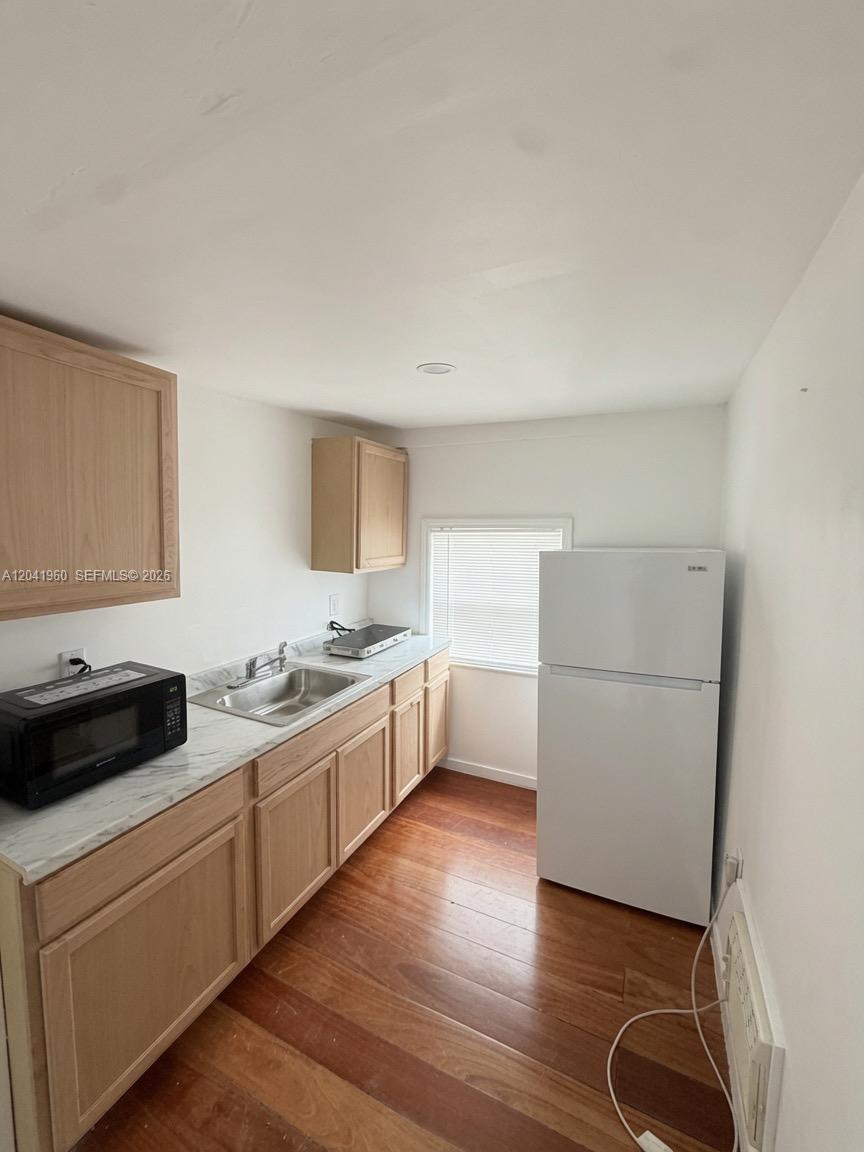 A small kitchen features light wood cabinets, a white refrigerator, and a stainless steel sink — 1340 Peri St # U, Opa-Locka FL 33054, OPA-LOCKA, FL