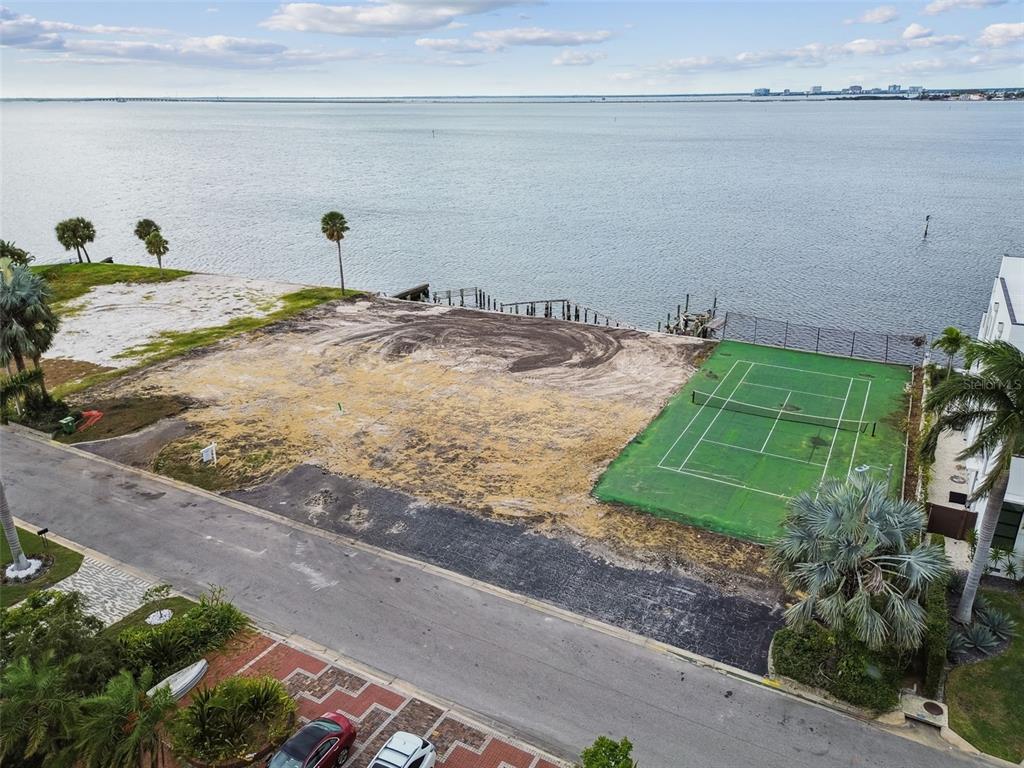 An aerial view shows a vacant waterfront lot with a tennis court and paved road — 5031 W SAN MIGUEL STREET, TAMPA, FL