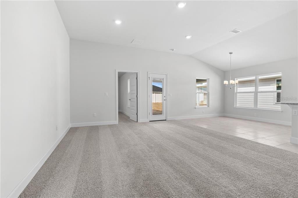 A spacious living area features gray carpeting, light walls, recessed lighting, and a glass door — 39 RIVERINA DRIVE, PALM COAST, FL