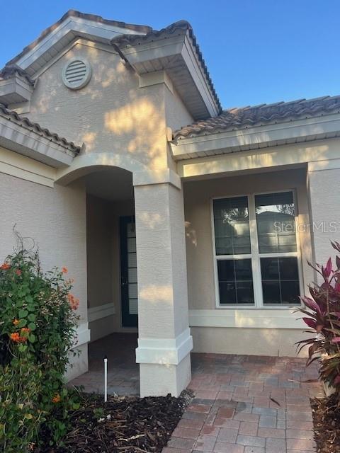 The exterior of a beige stucco house features a covered entryway and a large window — 6517 TAILFEATHER WAY, BRADENTON, FL